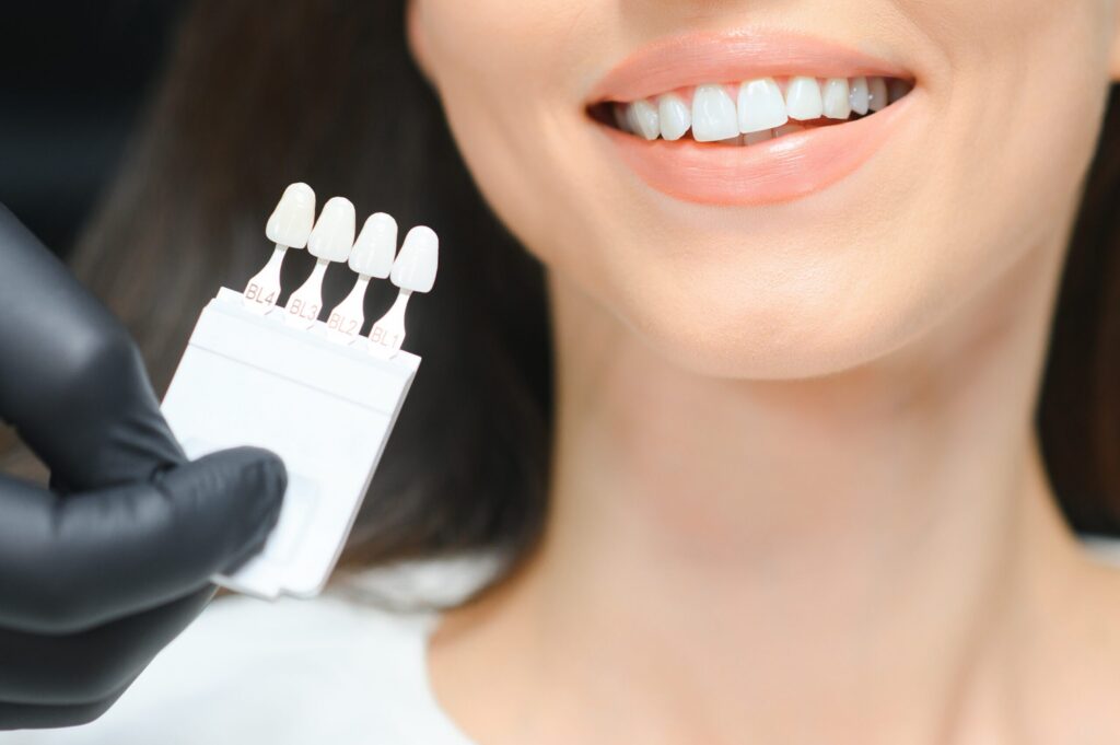 dentist checking and selecting color of young woman's teeth.